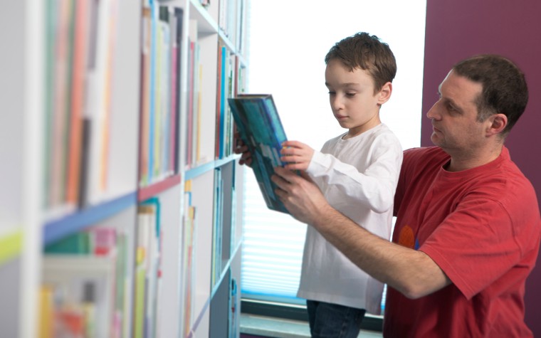 father and son choosing a book in the library