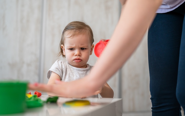 unhappy or angry looking toddler child playing with parent mother
