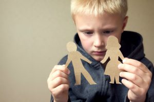 Child looking at paper cuttings of male and female figure to illustrate family problems