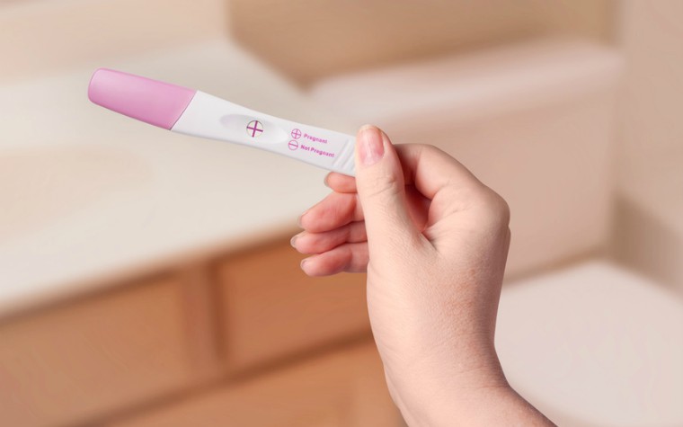 Young woman checking pregnancy test kit in bathroom
