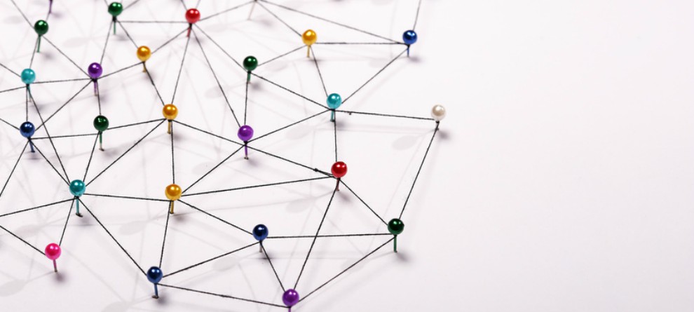 multicoloured pins connected in a network by thread