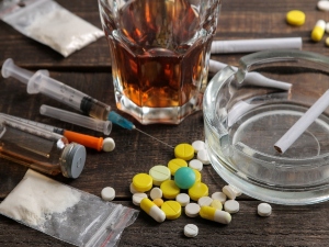 Various substances including alcohol, cigarettes, and drugs on a brown wooden table