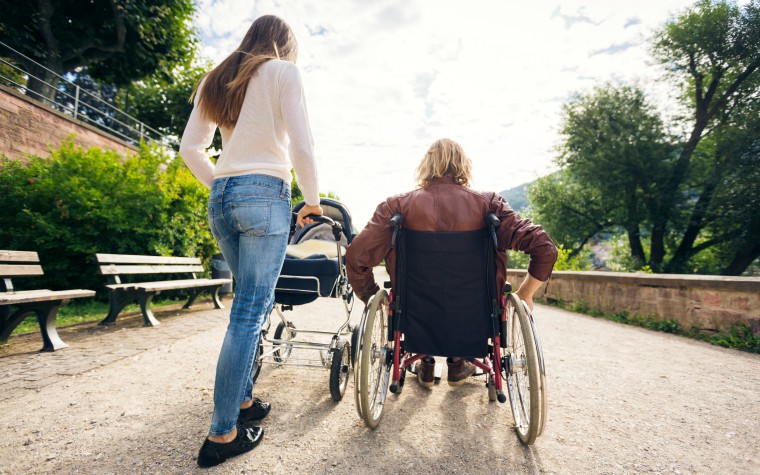 Young carer - pushes pram with parent in wheelchair