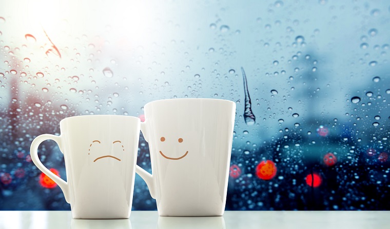 Two coffee cups with smiley face and sad face