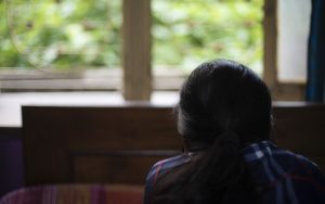 ack view of depressed young woman/girl looking out the window in bedroom