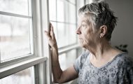 An older woman looking out of her window