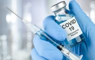 gloved hand holding covid vaccine