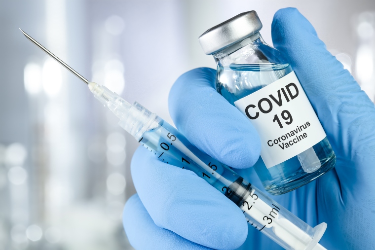 gloved hand holding covid vaccine