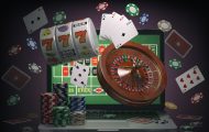 Online casino concept. Laptop with roulette, slot machine, casino chips and playing cards