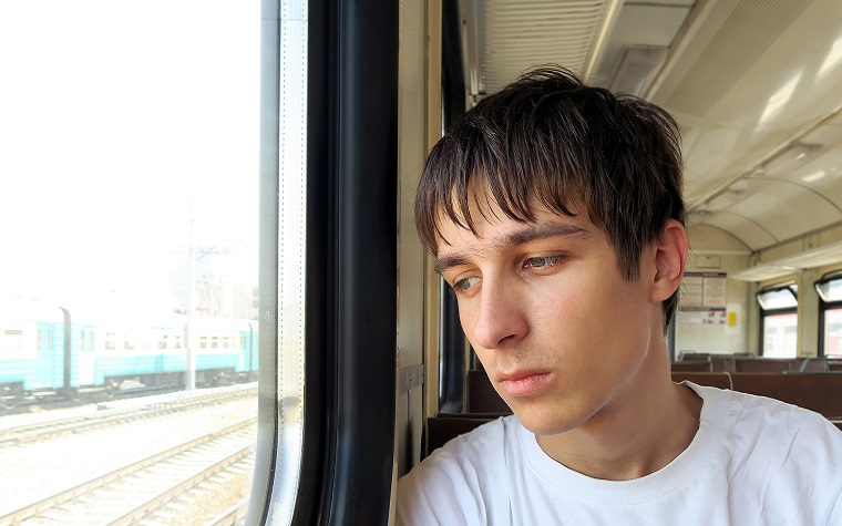 teenage boy looking out of a train window