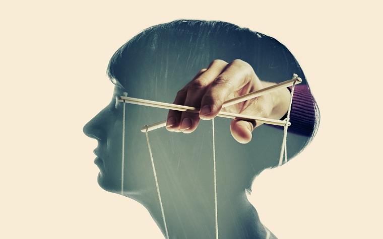 concept illustration of woman's head with a hand manipulating puppet strings inside - coercive control