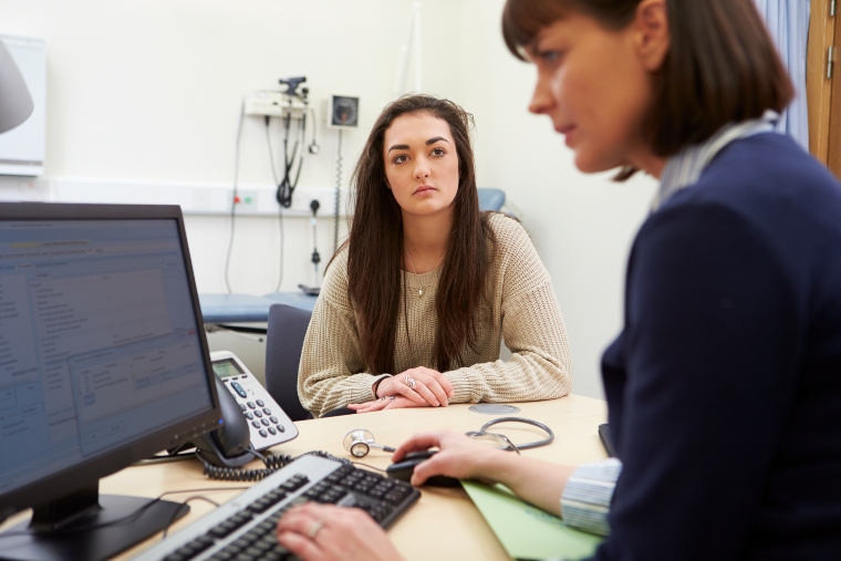 Female teenager talking to consultant in hospital
