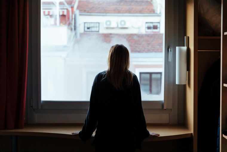 Woman with her back to the camera looking out of a window