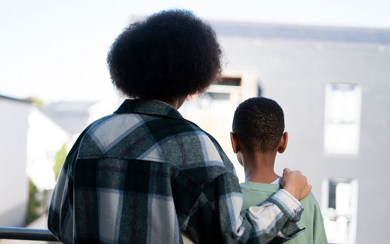 Mother and son standing on balcony, back view