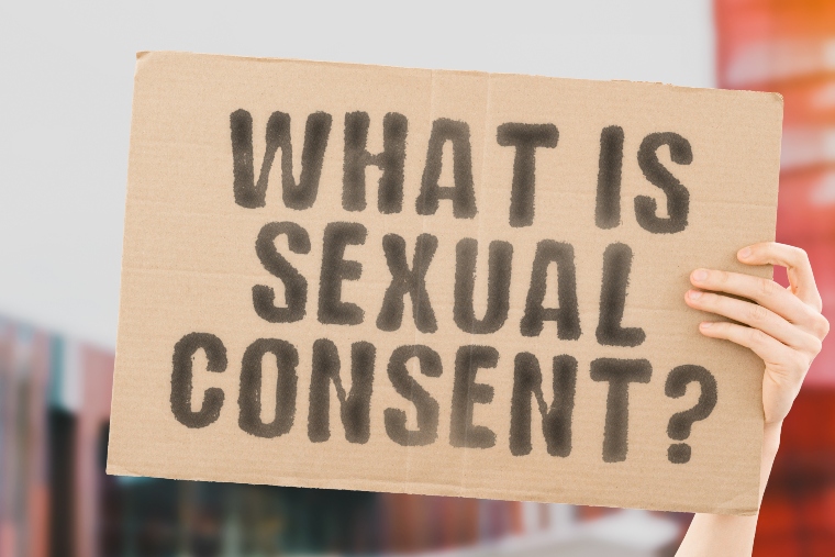 Hand holding sign that says 'what is sexual consent?'