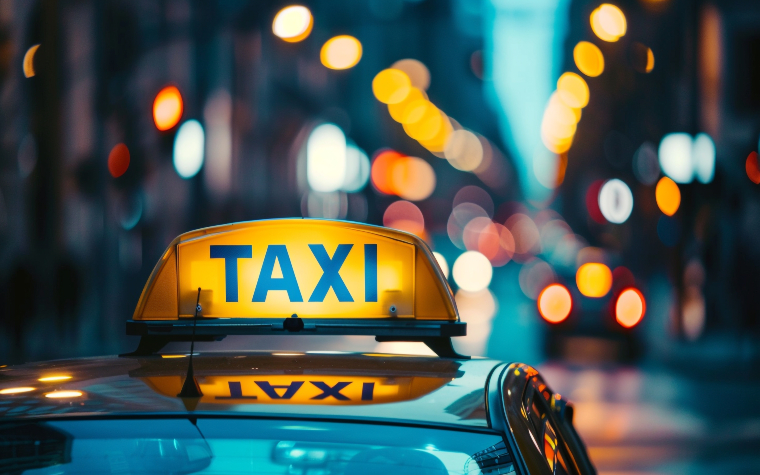 yellow taxi sign on top of car in city at night