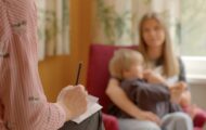 Social worker meeting with mother and young boy who is sitting in his mum's lap