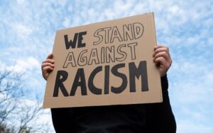 Person holding a placard reading 'we stand against racism'