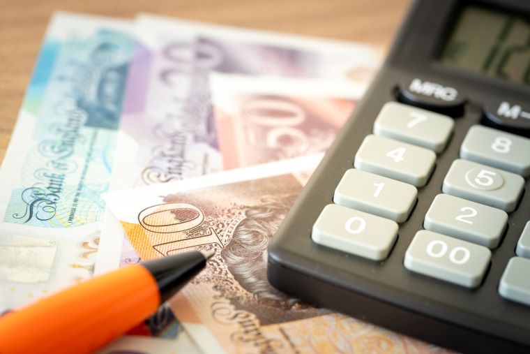 Bank notes, a pen and calculator on a table