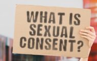 Hand holding up a sign that says 'what is sexual consent?'