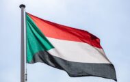 The flag of Sudan, the Republic of Sudan, horizontal red-white-black tricolour with a green triangle at the hoist.