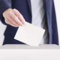 A person putting a vote in a ballot box