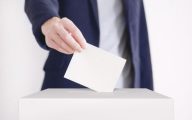 A person putting a vote in a ballot box