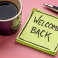 Post-it note with the welcome 'welcome back' next to a cup of coffee
