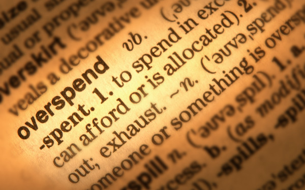 Close-up of dictionary page showing definition of the word 'overspend' (credit: danheighton / Adobe Stock)