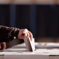 Hand of a person casting a vote into the ballot box during elections