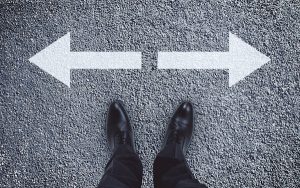 Image of pair of feet and arrows signifying a crossroads or change of direction (credit: peshkov / Adobe Stock)
