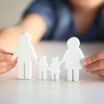 Image of child holding cutouts of a family (credit: Africa Studio / Adobe Stock)