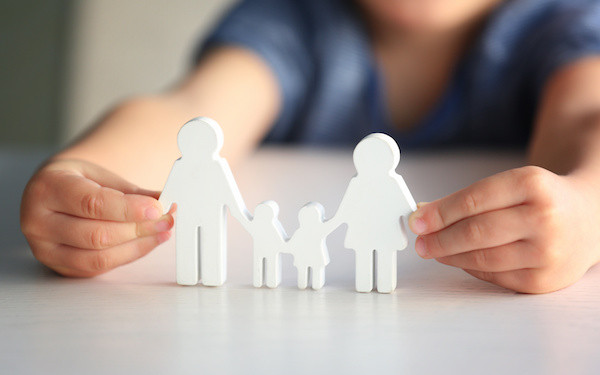 Image of child holding cutouts of a family (credit: Africa Studio / Adobe Stock)