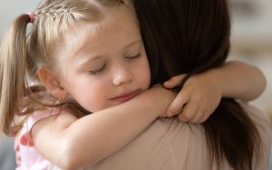 Image of girl embracing foster mother (credit: fizkes / Adobe Stock)
