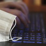 Image of PPE mask resting on laptop (credit: raquel / Adobe Stock)