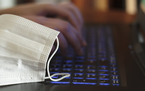 Image of PPE mask resting on laptop (credit: raquel / Adobe Stock)