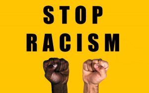 African black fist and caucasian white fist raised calling for freedom and equality on a yellow background. Multicultural fists raised. Stop racism.