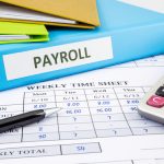 Image of payroll file and calculator (credit: vinnstock / Adobe Stock)