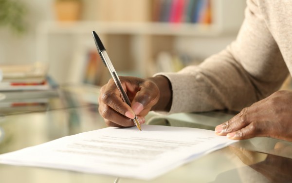 Man signing document on a desk at home
