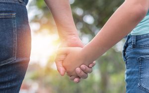 Image of female child holding female adults' hand (credit: Chinnapong / Adobe Stock)