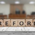 Reform sign on a desk with a blurry background of a court room