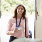 Female care worker on home visit showing her ID, close up