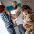 A child hugs a teddy bear in the foreground while in the background a person with a beard is holding someone with red hair threateningly