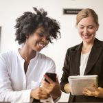 A white and a Black woman talking in the workplace