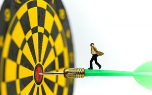 Miniature people: businessman on dart arrow hitting in the target center of dartboard,Target business, achieve and victory concept .