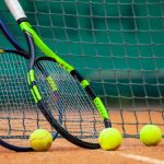 wo tennis rackets and balls leaned against the net.