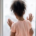 Child looking out of window longingly
