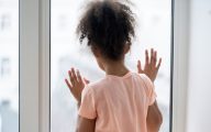 Child looking out of window longingly