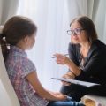 Woman social worker talking to girl. Child psychology, mental health.