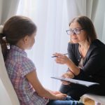 Woman social worker talking to girl. Child psychology, mental health.